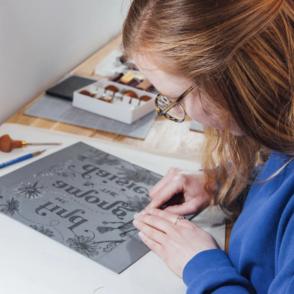 Kimber drawing a detailed illustration at her desk.